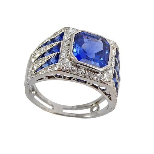 Art Deco single stone sapphire and diamond cluster ring, c.1925, the canted square sapphire of approximately 4.00ct, between calibre sapphire and diamond dart shoulders,